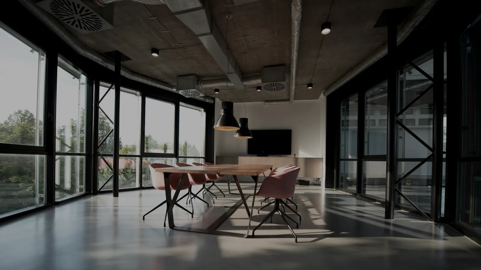 Salle de réunion contemporaine et vide, longue table et sièges alignés devant de grandes baies vitrées.