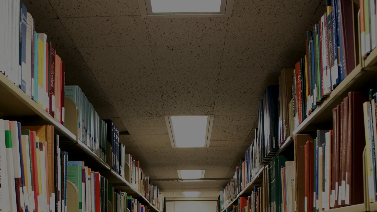 Allée d’une bibliothèque bordée de rayonnages remplis d’ouvrages, évoquant la sélection d’informations pertinentes.